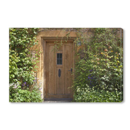 Obraz na płótnie Brązowe drewniane drzwi w starym tradycyjnym angielskim domu z kwiatami w letni dzień