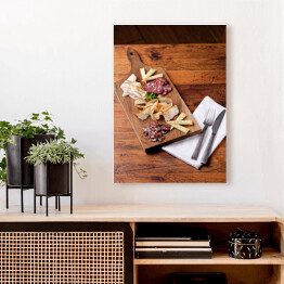 Obraz na płótnie Sery i wędliny sery na drewnianej desce na rustykalnym stole