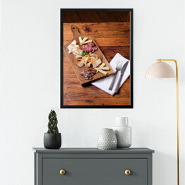 Obraz w ramie Sery i wędliny sery na drewnianej desce na rustykalnym stole
