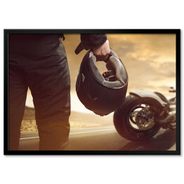 Plakat w ramie Motocyklista stojący z kaskiem na drodze