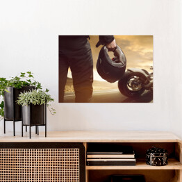 Plakat samoprzylepny Motocyklista stojący z kaskiem na drodze
