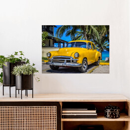 Plakat Żółty amerykański klasyczny samochód zaparkowany pod palmami na plaży w Varadero na Kubie 