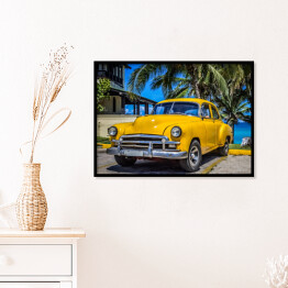 Plakat w ramie Żółty amerykański klasyczny samochód zaparkowany pod palmami na plaży w Varadero na Kubie 