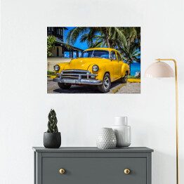Plakat Żółty amerykański klasyczny samochód zaparkowany pod palmami na plaży w Varadero na Kubie 