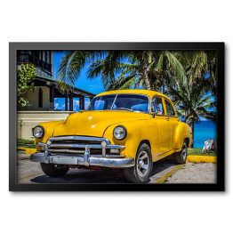 Obraz w ramie Żółty amerykański klasyczny samochód zaparkowany pod palmami na plaży w Varadero na Kubie 