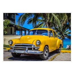 Plakat samoprzylepny Żółty amerykański klasyczny samochód zaparkowany pod palmami na plaży w Varadero na Kubie 