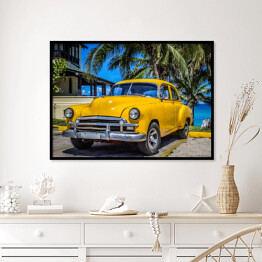 Plakat w ramie Żółty amerykański klasyczny samochód zaparkowany pod palmami na plaży w Varadero na Kubie 