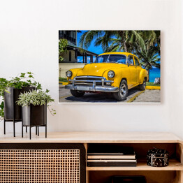 Obraz na płótnie Żółty amerykański klasyczny samochód zaparkowany pod palmami na plaży w Varadero na Kubie 