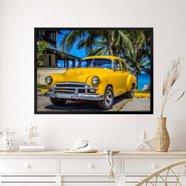 Obraz w ramie Żółty amerykański klasyczny samochód zaparkowany pod palmami na plaży w Varadero na Kubie 