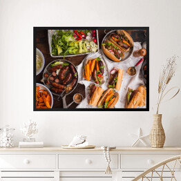 Obraz w ramie Grill - kiełbasa, kanapki ze smażonymi ziemniakami i sosem podawanymi na rustykalnym stole