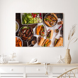 Obraz na płótnie Grill - kiełbasa, kanapki ze smażonymi ziemniakami i sosem podawanymi na rustykalnym stole