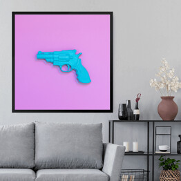 Obraz w ramie Niebieski pistolet na różowym tle