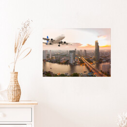Plakat Samolot na tle panoramy miasta o zachodzie słońca