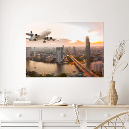 Plakat samoprzylepny Samolot na tle panoramy miasta o zachodzie słońca