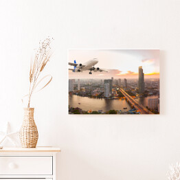 Obraz na płótnie Samolot na tle panoramy miasta o zachodzie słońca