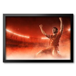 Obraz w ramie Piłkarz świętuje bramkę na przydymionym czerwonym tle 