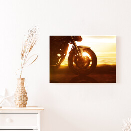 Obraz na płótnie Koło motocyklu na tle złocistego zachodu słońca