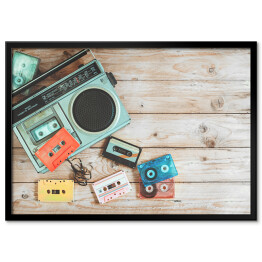 Plakat w ramie Widok z góry - radio i kasety z wyciągniętą taśmą na drewnianym stole