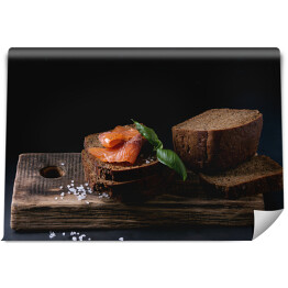 Fototapeta Chleb żytni z wędzonym łososiem, sól morska i świeża bazylia na drewnianej desce 