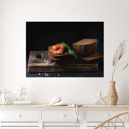 Plakat Chleb żytni z wędzonym łososiem, sól morska i świeża bazylia na drewnianej desce 