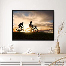 Obraz w ramie Młoda para jadąca rowerami o zachodzie słońca