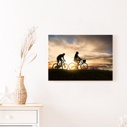 Obraz na płótnie Młoda para jadąca rowerami o zachodzie słońca