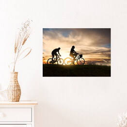 Plakat Młoda para jadąca rowerami o zachodzie słońca