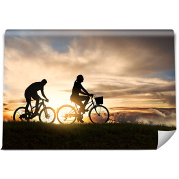 Fototapeta winylowa zmywalna Młoda para jadąca rowerami o zachodzie słońca