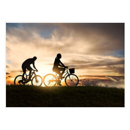 Plakat samoprzylepny Młoda para jadąca rowerami o zachodzie słońca
