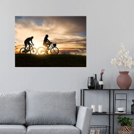 Plakat samoprzylepny Młoda para jadąca rowerami o zachodzie słońca