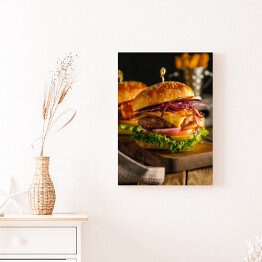 Obraz na płótnie Świeży hamburger z mięsem, bekonem, serem i warzywami na drewnianej desce
