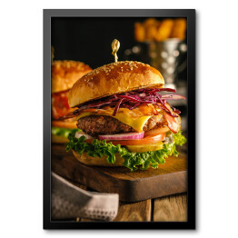 Obraz w ramie Świeży hamburger z mięsem, bekonem, serem i warzywami na drewnianej desce