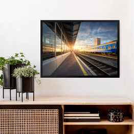 Obraz w ramie Niebieski pociąg pasażerski na stacji kolejowej o zmierzchu