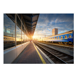 Plakat samoprzylepny Niebieski pociąg pasażerski na stacji kolejowej o zmierzchu