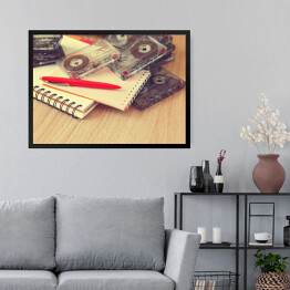 Obraz w ramie Notatnik, pióro i kasety na drewnianym stole