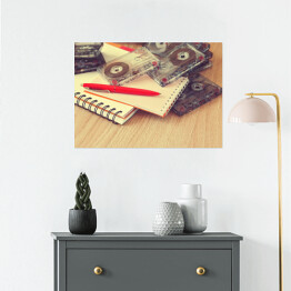 Plakat Notatnik, pióro i kasety na drewnianym stole