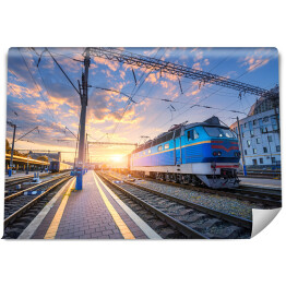 Fototapeta Błękitny pociąg na stacji kolejowej o zmierzchu