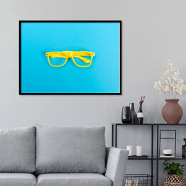 Plakat w ramie Para żółtych okularów na jasnoniebieskim tle