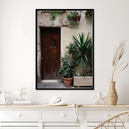 Plakat w ramie Stary dom z roślinami w garnkach i drewnianymi ciemnobrązowymi drzwiami