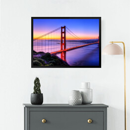 Obraz w ramie Most Golden Gate na tle wody w różowych barwach oraz złocisto błękitnego nieba