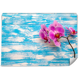 Gałąź purpurowej orchidei na błękitnym drewnianym stole
