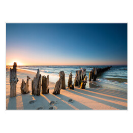 Plakat samoprzylepny Stary drewniany falochron i zachód słońca na plaży Morza Bałtyckiego, Polska