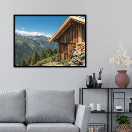 Plakat w ramie Drewniana chata na wzgórzu z wysokimi górami w tle