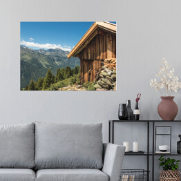 Plakat samoprzylepny Drewniana chata na wzgórzu z wysokimi górami w tle