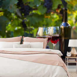 Fototapeta Dwa kieliszki czerwonego wina i butelki w winnicy