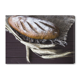 Obraz na płótnie Chleb żytni na drewnianym stole obok żyta