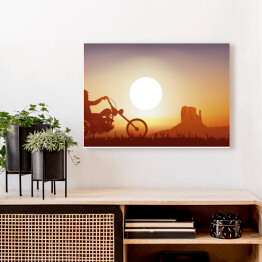 Obraz na płótnie Motocyklista na tle zachodu słońca w pomarańczowym i niebieskim odcieniu