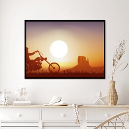 Plakat w ramie Motocyklista na tle zachodu słońca w pomarańczowym i niebieskim odcieniu