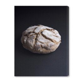 Obraz na płótnie Okrągły rustykalny francuski chleb pełnoziarnisty z rodzynkami na czarnym tle