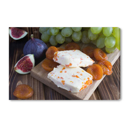 Obraz na płótnie Miękki ser z suszonymi morelami i owocami na drewnianej desce do krojenia